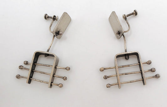 A pair of vintage silver-toned drop earrings with a geometric, guitar-fret-like design featuring horizontal bars and small round tips, photographed on a plain white background.